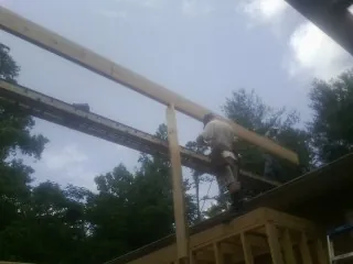 Carpenter setting a ridge beam over a new addition frame — Ice Dam Removal by Roofing Brothers in Portal
