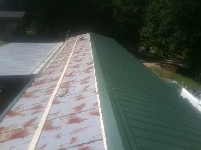 Old rusted panels beside newly installed green metal roofing — Wind Damage Roof Repair by Roofing Brothers in Portal