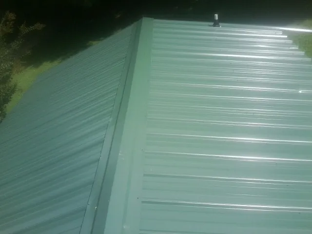 New green metal panels meeting at the ridge of a roof — Flat Roof Repair work by our crew in Portal