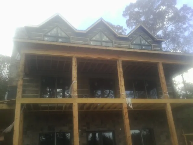 Dormers and porch framing on a large log home under construction — Roof Coating work by our crew in Portal