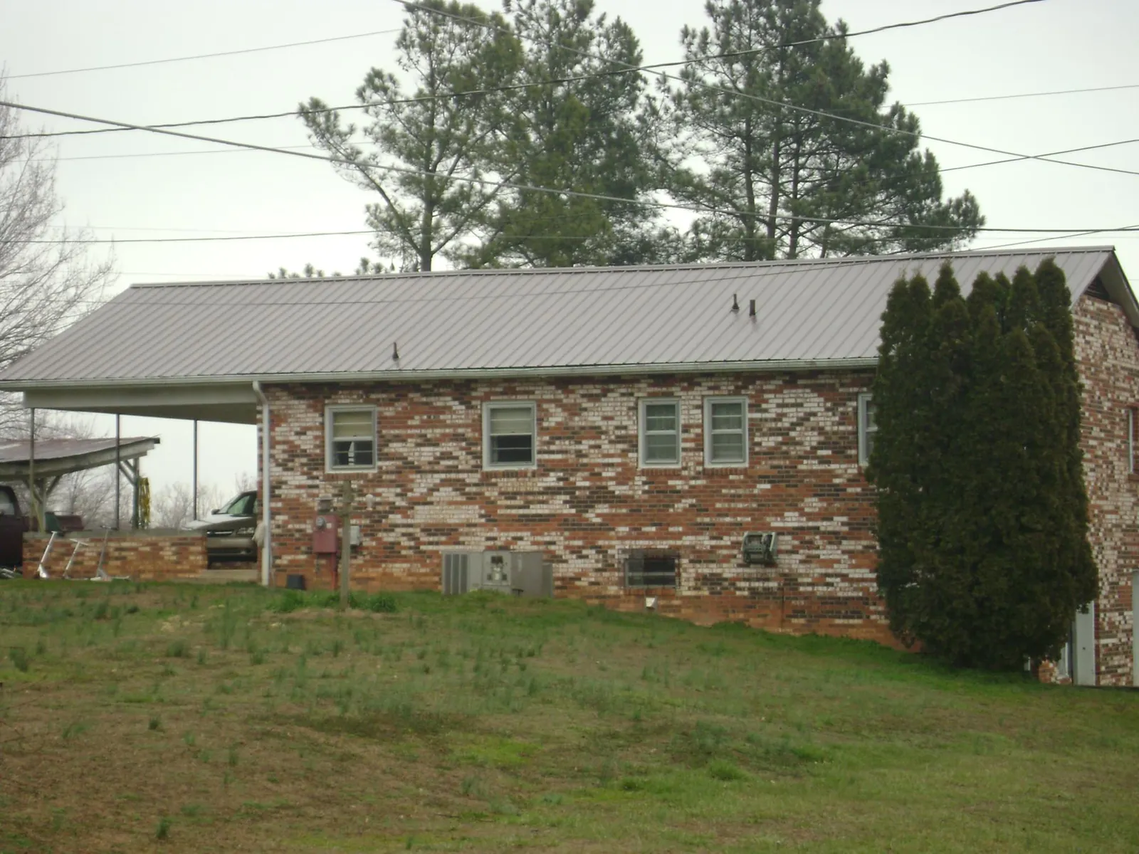 Gray metal roof on a brick split level home with a carport in Portal