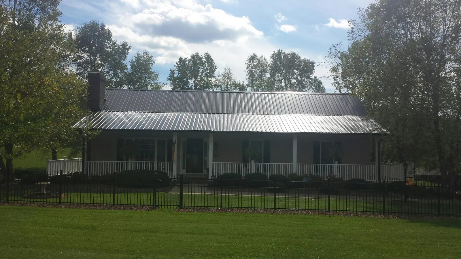 Gray metal roof on a brick ranch with a full width front porch — Gutter Guard Installation work by our crew in Portal