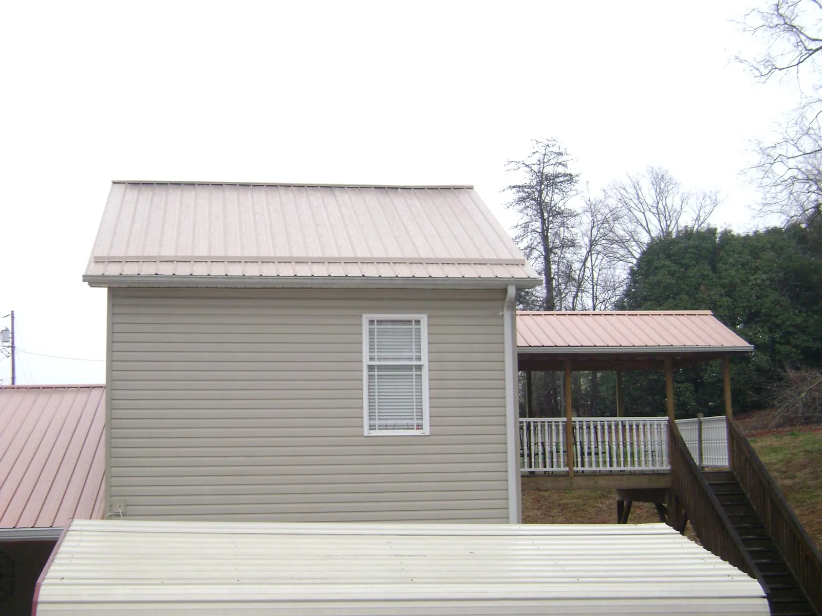 Tan metal roofs on a two story addition and attached porch, from a Roof Replacement job in Portal