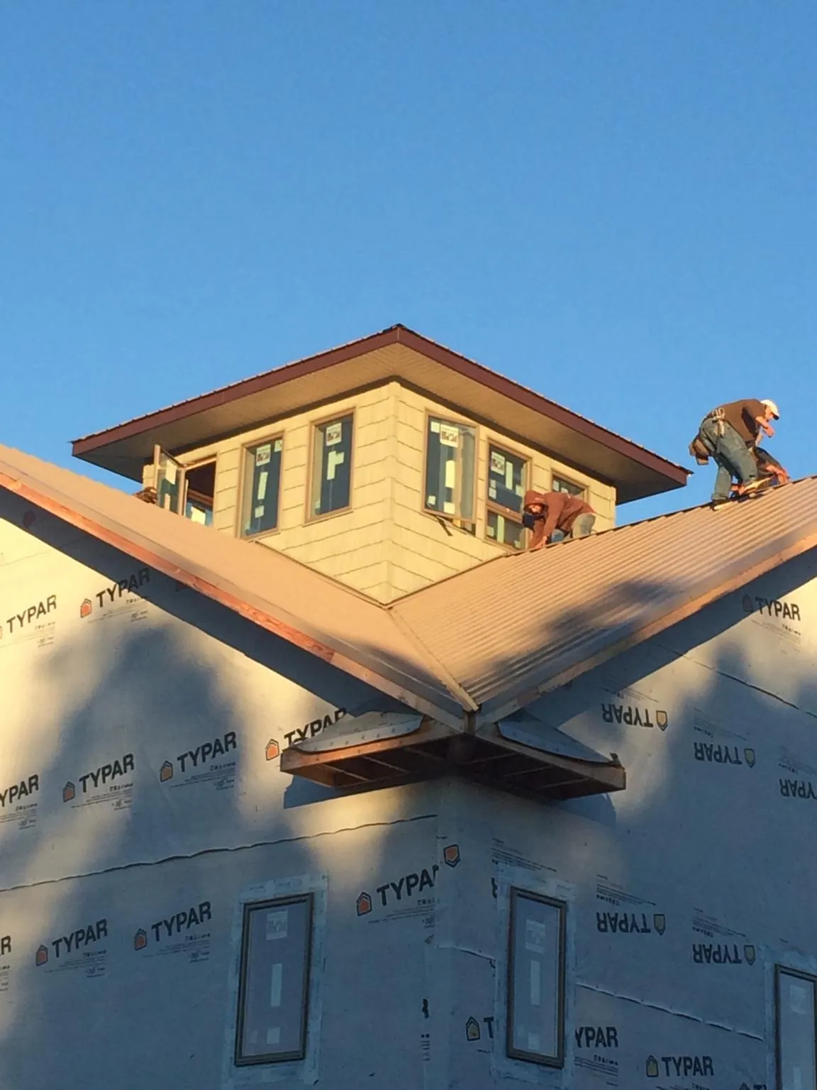 Roofers working around a rooftop cupola on a new metal roof at sunset — Roof Waterproofing in Portal by Roofing Brothers